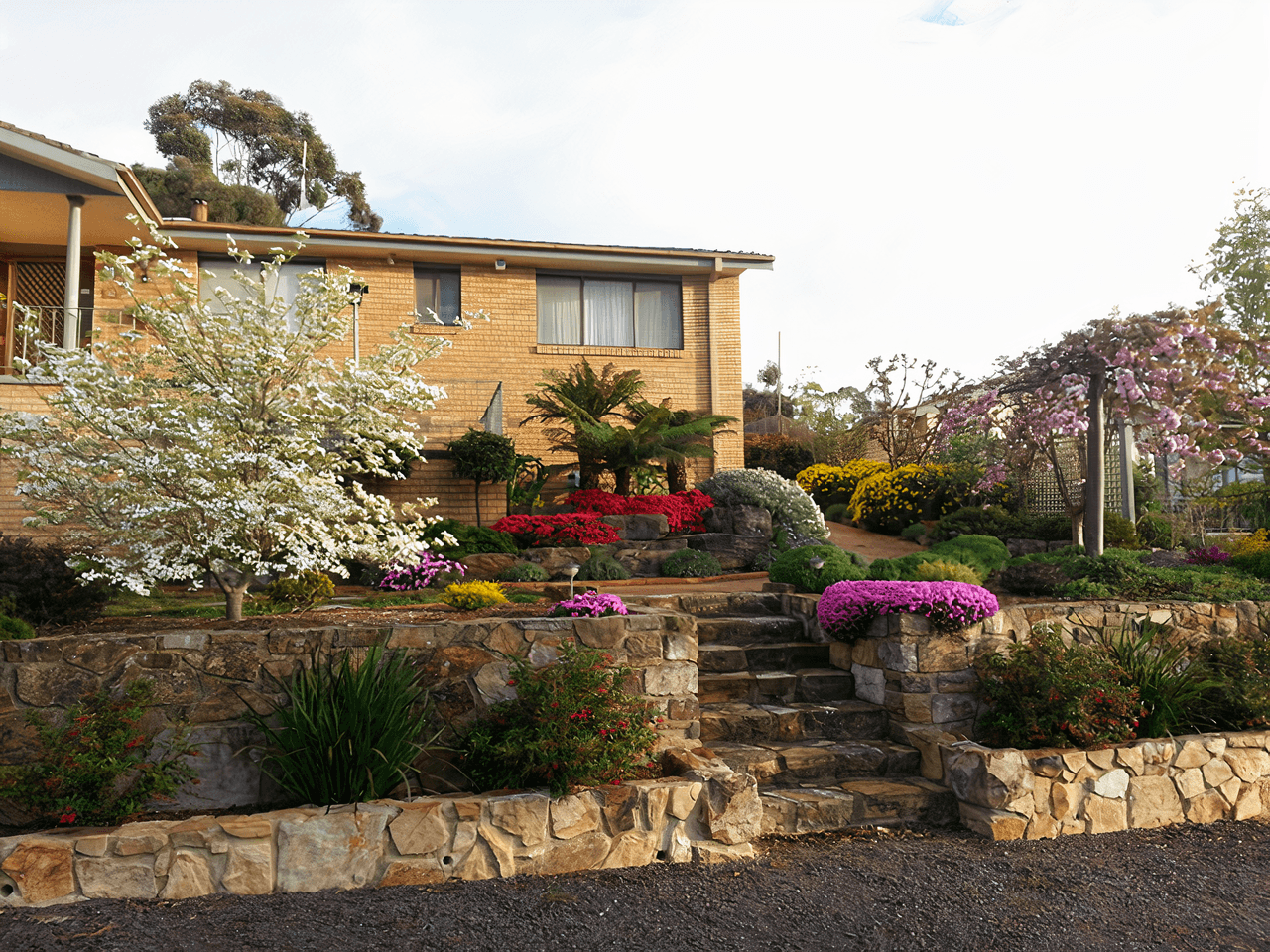 A beautiful stone retaining wall with garden beds by Dan and Dan Landscaping